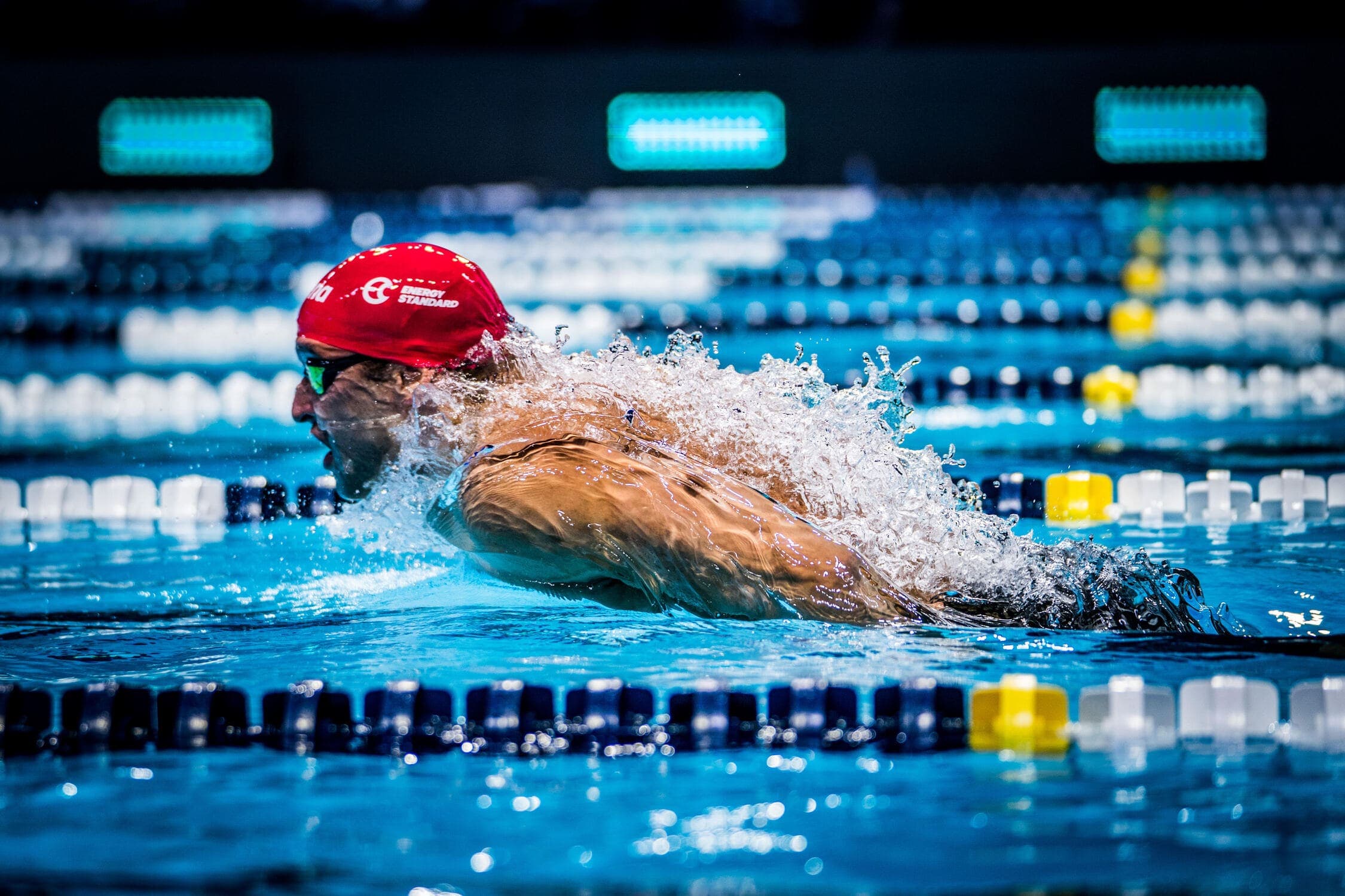 Competitive swimmer racing butterfly in an illuminated pool